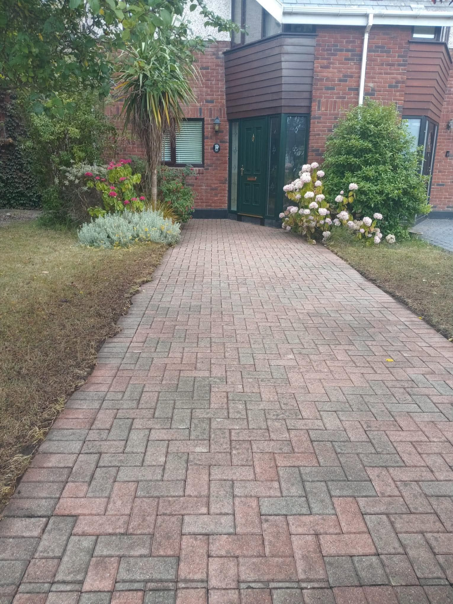 Brick paved front driveway weeded, edged and washed clean up to a green front door