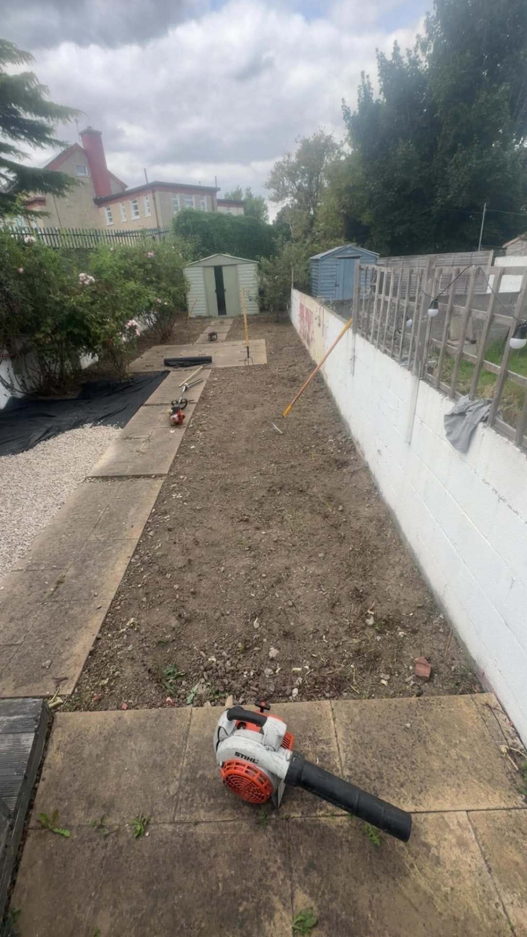 Same garden dug back to level bare soil with the paving swept and tools on site