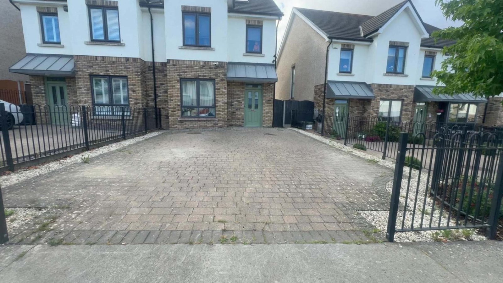 Block paved estate driveway dulled with dirt and weeds growing through the joints